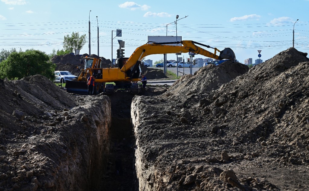 Utility trench with excavator and excavated material